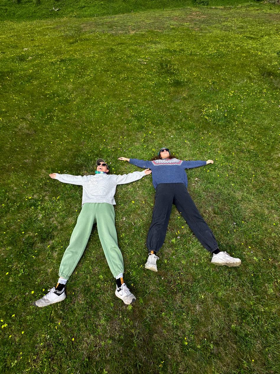 Two friends lying in the grass, arms spread wide